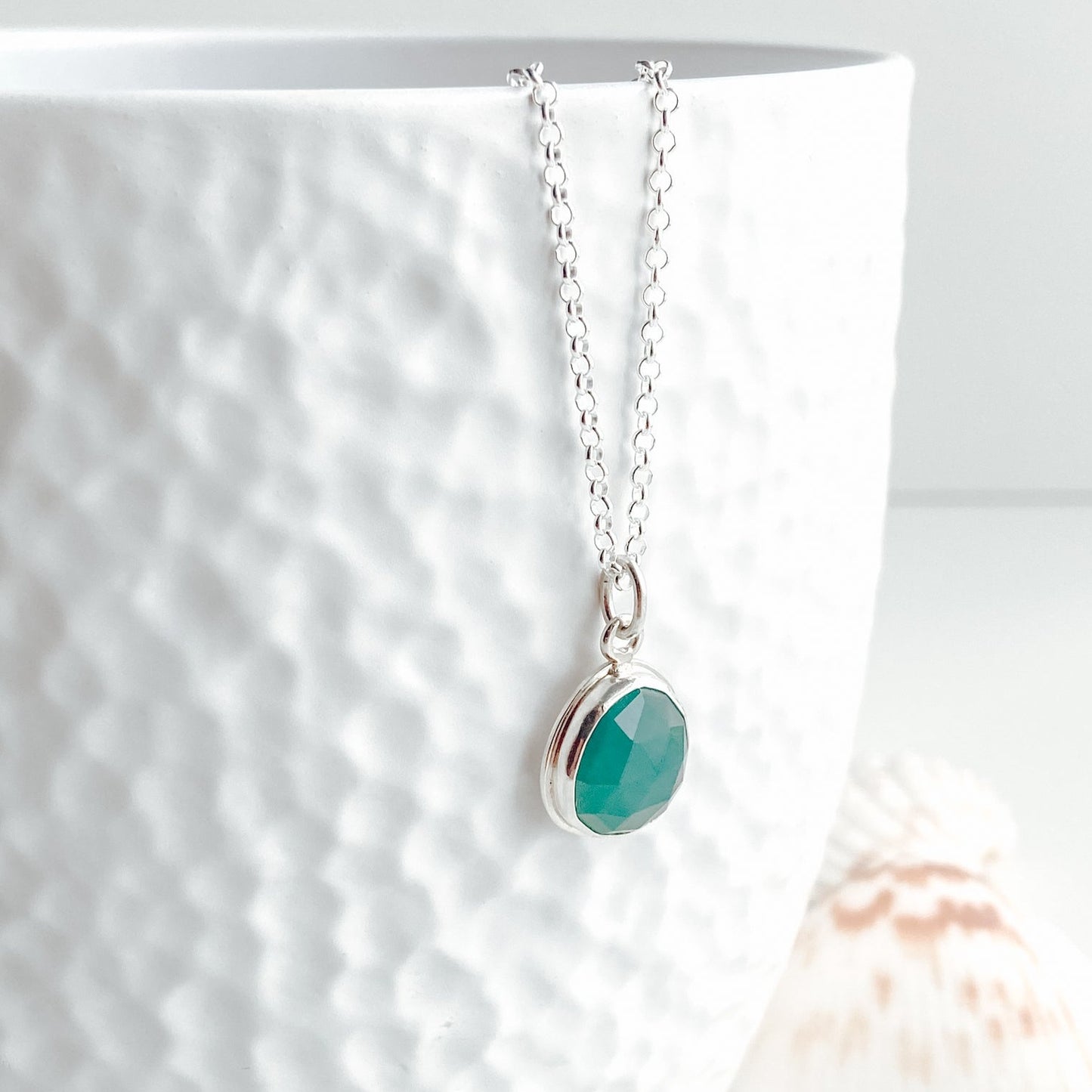 Gandiderite rose cut and silver pendant displayed on a white vase
