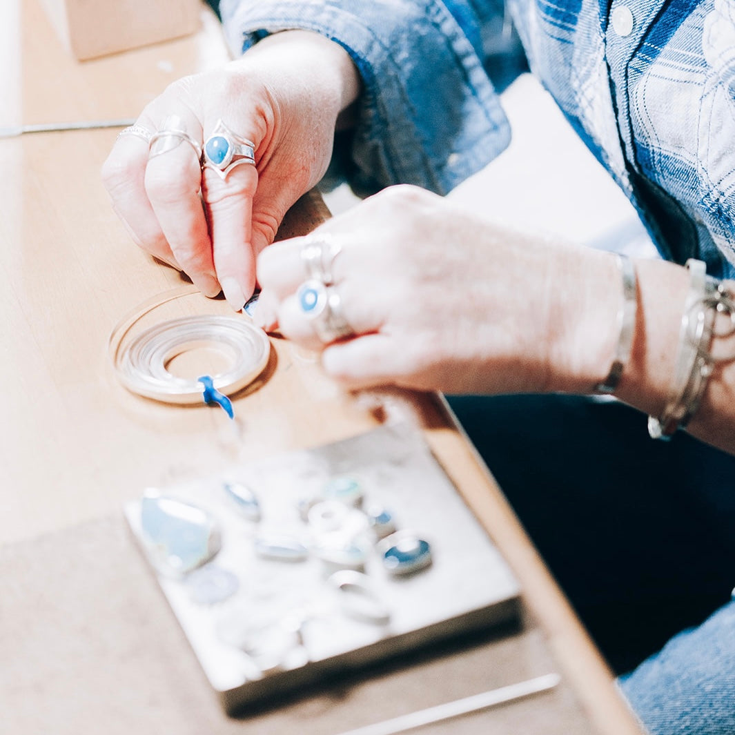A photo of a jewelry designer creating silver jewelry by hand. 