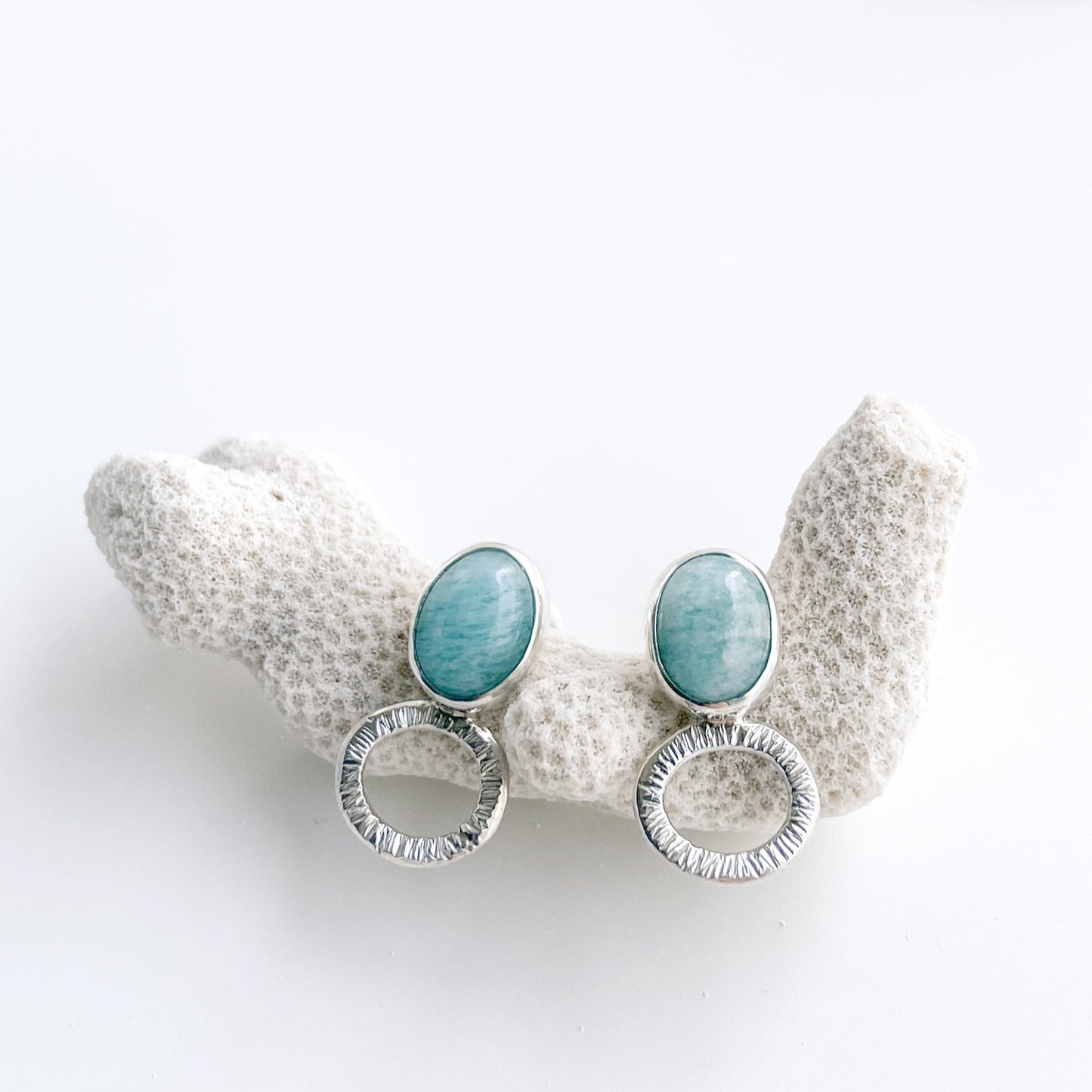 Amazonite and textured silver stud earrings displayed or a piece or white coral