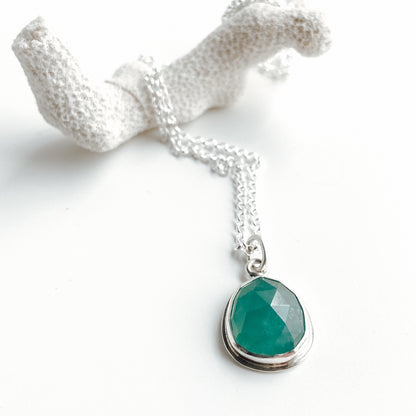 Teal rose cut gandiderite and silver pendant on a white background with white coral