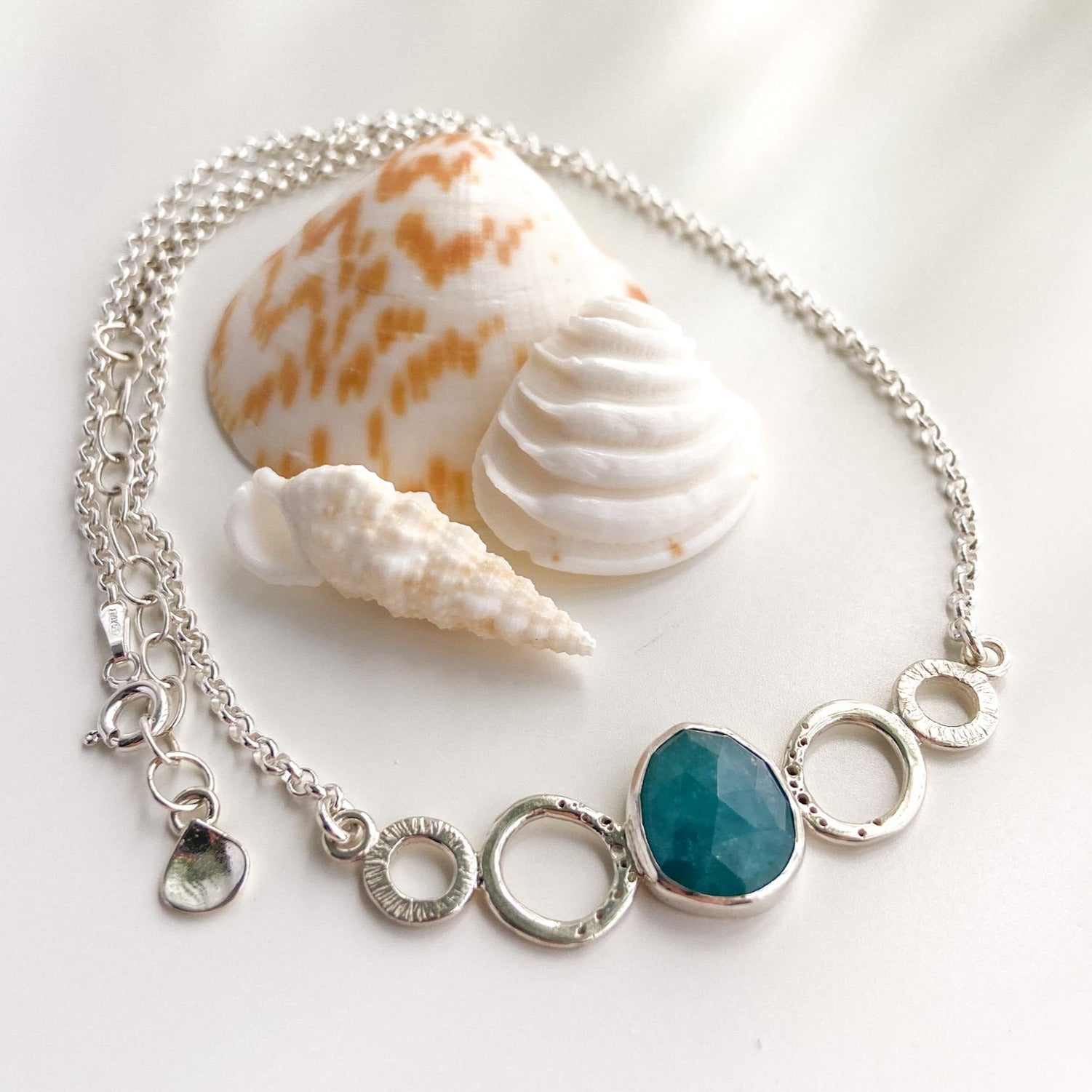 Teal green rose cut gandiderite gemstone and silver necklace displayed with shells