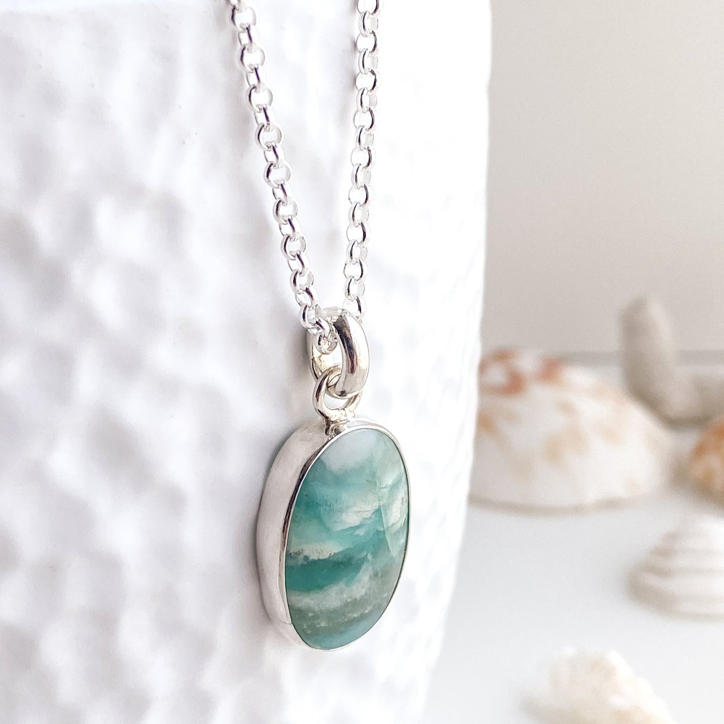 Opalized wood gemstone pendant in shades of aqua, teal, and white in a simple silver bezel setting.