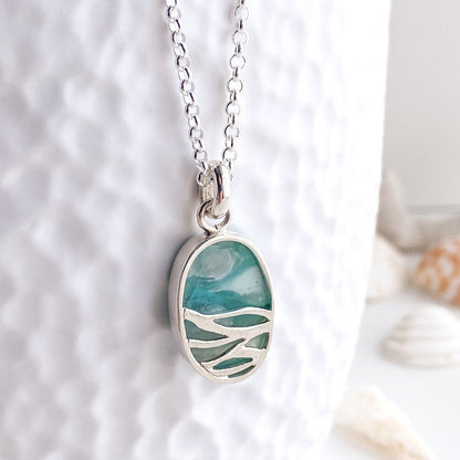 Reverse view of the opalized wood pendant showcasing the wave cutout design
