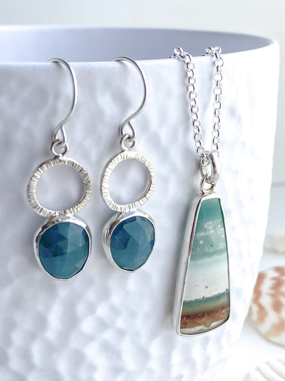 Teal blue/green textured silver earrings with opalized wood pendant that has a beach scene