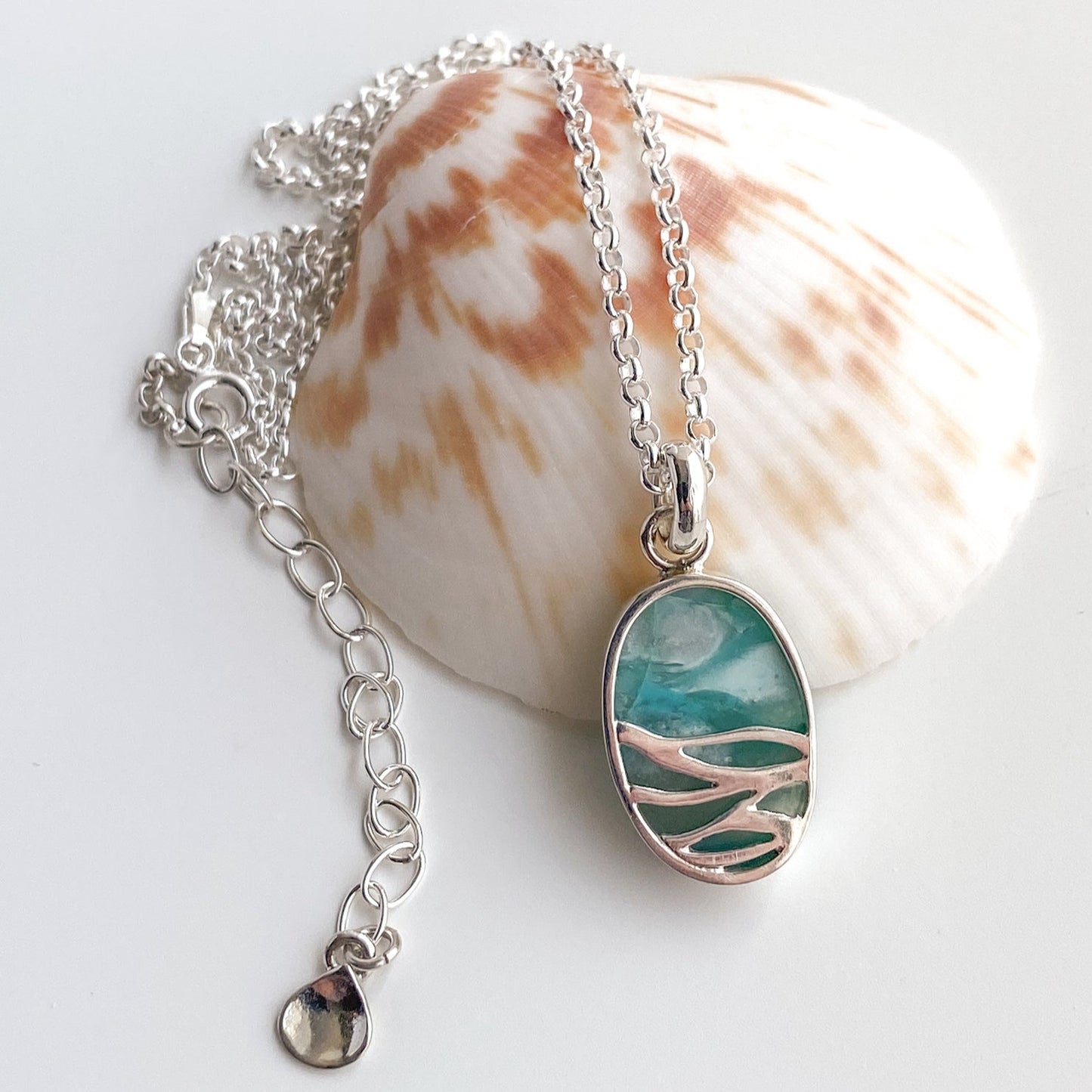 closeup view of the reverse side of the pendant revealing the waves cut out design and the backside of the teal and aqua stone