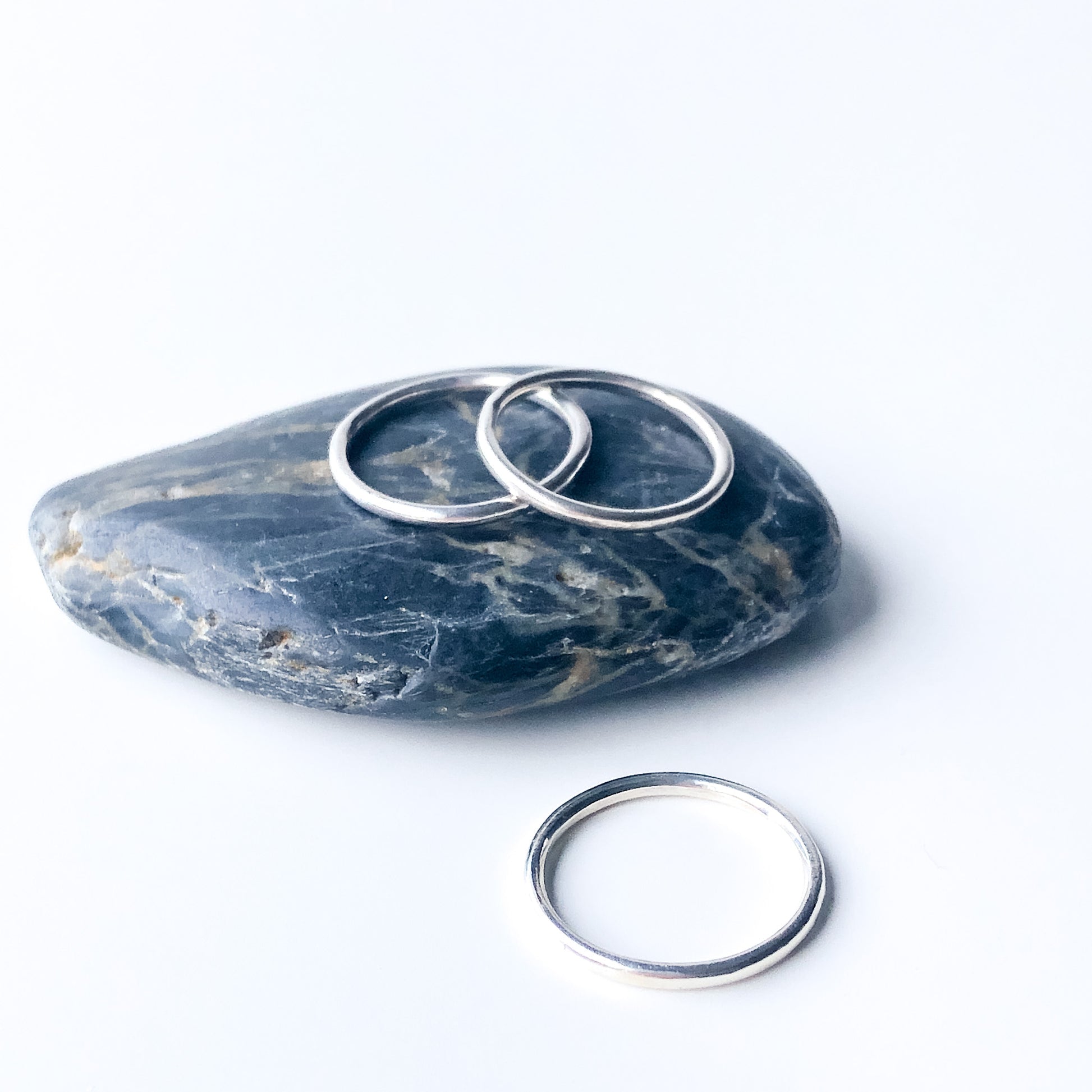 three polished silver rings on a rock