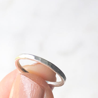 Hammered textured stacking ring held up between a thumb and fore finger