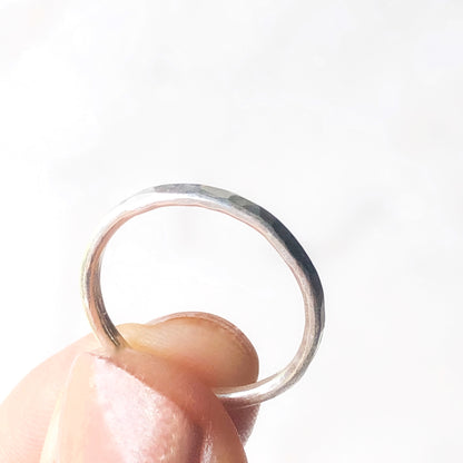 Another view of a single stacking ring being held between a thumb and fore finger