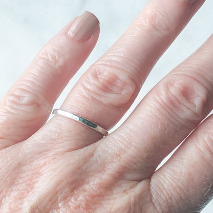  a single silver stacking ring being worn on a ring finger