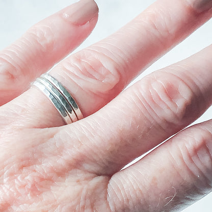 a trio of hammered silver stacking rings being worn