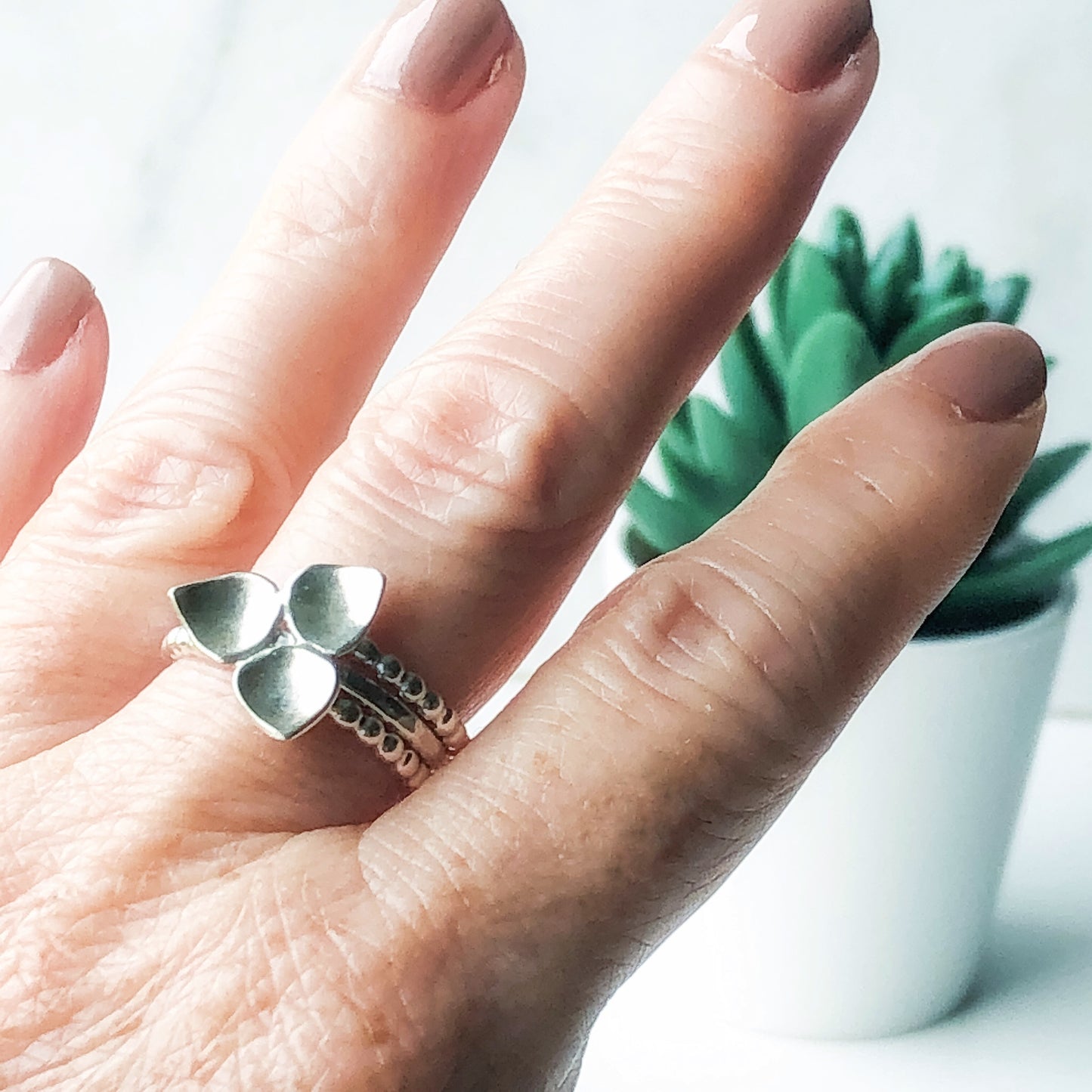 Silver trillium ring worn with two beaded silver stacking rings