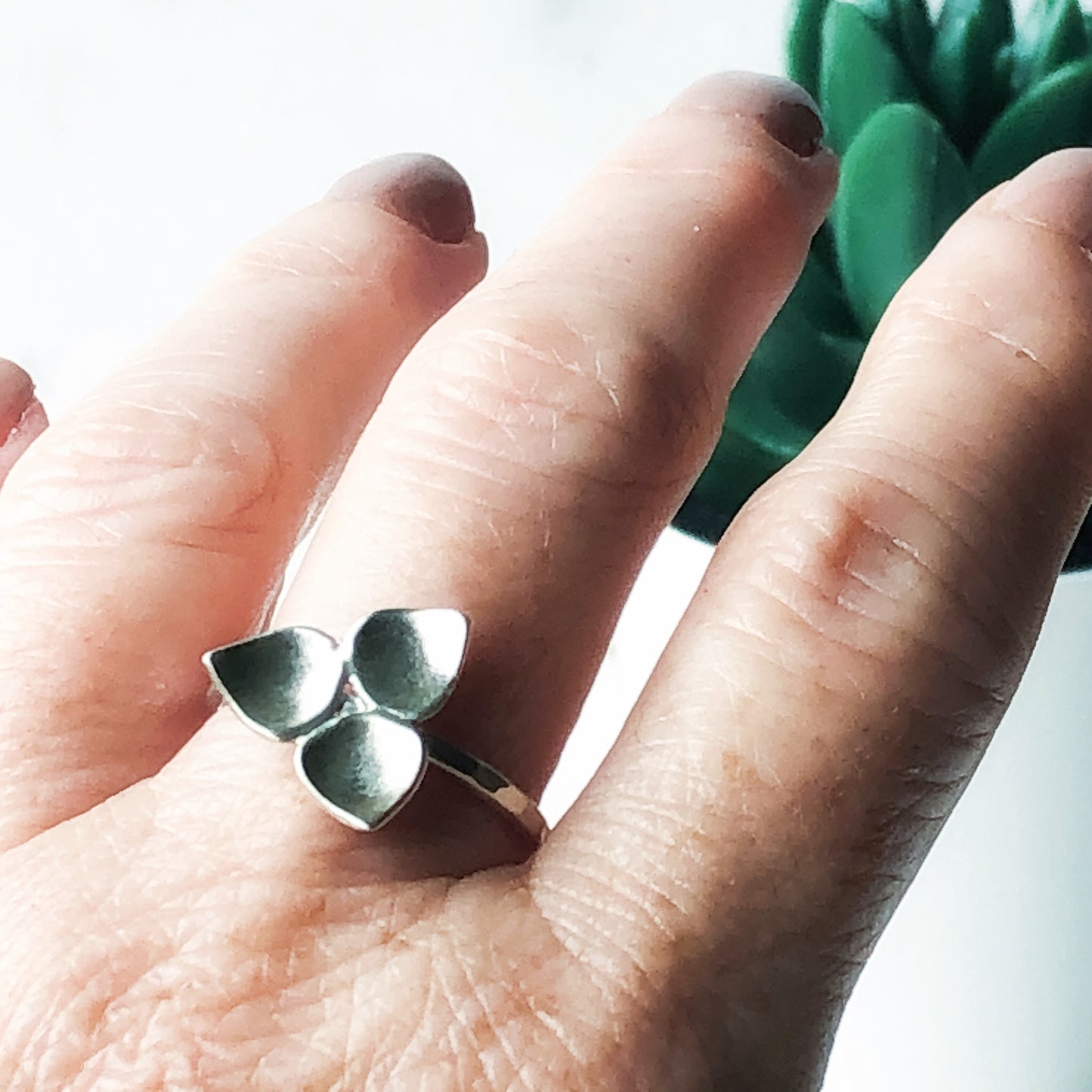 Silver trillium ring on a finger