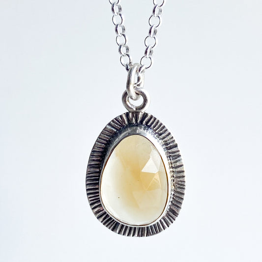 A stunning pear shaped rose cut citrine gemstone pendant in sterling silver with a line stamped textured border.